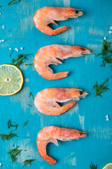 Frozen boiled shrimps on turquoise colored wooden board. Seafood product