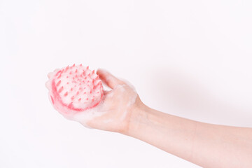 Scalp massager in hand and in foam against white background.