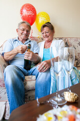 Retirement: Opening the Champagne. A senior couple popping the prosecco cork as they celebrate retirement. From a series of related images.