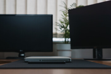 a wooden table with two screens and a laptop