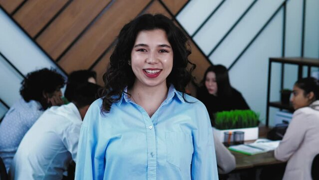 Portrait of Happy smiling middle eastern turkish female student standing in class and looking at camera. Classmates students are on background. Study at university or college, education concept. 