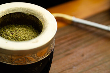 Traditional Argentinian yerba mate tea in a calabash gourd with bombilla stick against wooden...