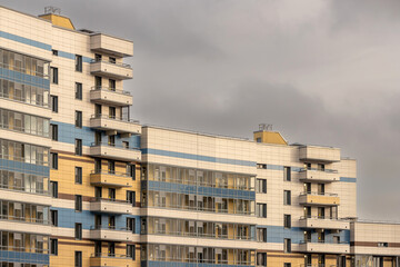 Fragment of a residential apartment building against the sky with gray clouds