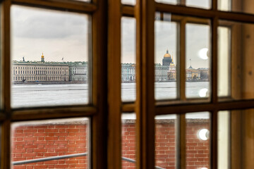 View of the embankment of the Neva River and St. Isaac's Cathedral in St. Petersburg, Russia, through a vintage window with a wooden frame on a cloudy winter day