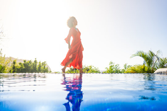 Woman with red dress next to an outdoor tropical pool