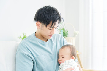 家で昼寝をする赤ちゃんを抱っこする父親