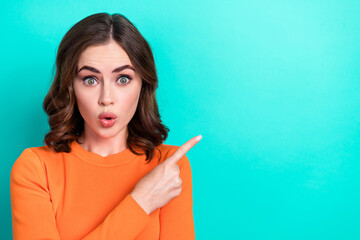 Photo of charming girl pouted lips wear trendy shirt shocked breaking news reaction finger point empty space isolated on aquamarine color background