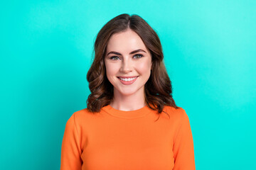 Closeup portrait of young charming positive smiling lady brown curly hairstyle wear orange stylish top good mood isolated on cyan color background