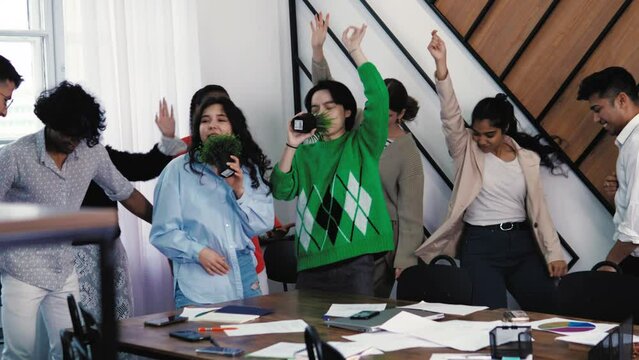 Careless young people students colleagues having party at office, dancing, singing karaoke with microphone, throwing papers away in air. The end of the day, week. Weekends, holidays, vacation. Student