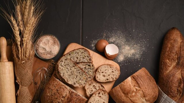 slide multi grain sourdough bread and sliced Baguette with Whole Wheat Flour on black stone background, Homemade bakery concept, pan motion