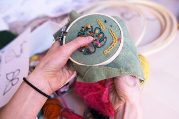 Hands of girl/woman/female sewing small embroidery pattern in a tiny wooden frame, linen....
