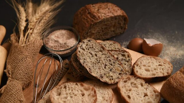 slide multi grain sourdough bread and sliced Baguette with Whole Wheat Flour on black stone background, Homemade bakery concept, pan motion