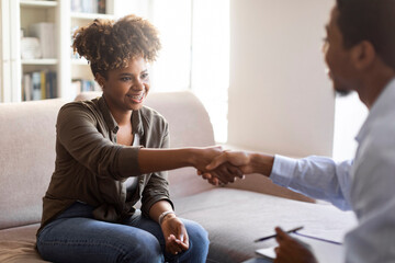 Happy black woman handshaking with man psychologist after therapy session - obrazy, fototapety, plakaty