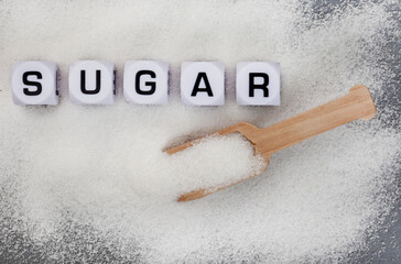 Sugar written in letter dice on white sugar granules
