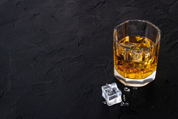 Glass of golden whiskey with ice. Strong alcoholic drink background