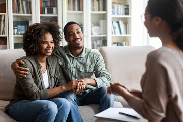 Happy black couple sitting in counselor office, successful marital therapy