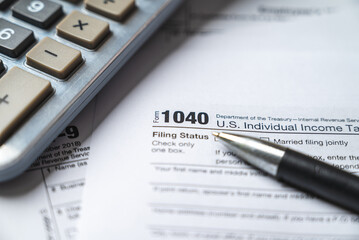 Financial time tax return forms with pen and calculator