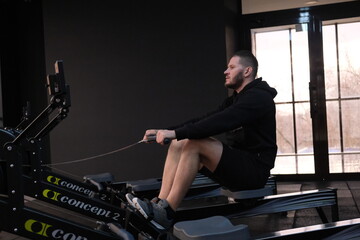  February 21, 2023 Ukraine, Dnipro. Rowing machine firm Concept 2. A man on a workout in the gym with his own weight. aeromagnetic simulator. Scandinavian traction for strength work of the back muscle © Mary_muis/stoker ua