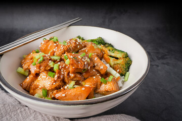 Chopsticks with Delicious sweet chopping chicken rice, sesame seeds, sliced spring onions, broccoli, and vegetables. Asian food, Japanese food. Close up