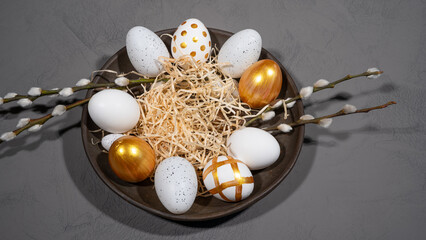 Obraz premium HAPPY EASTER holiday celebration backgroud banner - Easter nest with gold painted easter eggs and catkins on concrete table texture, top view......