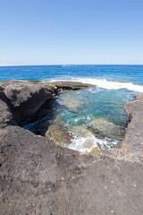 Views of a natural pool formed by rocks. Turquoise ocean. Gray volcanic rock formation. La Caleta, Tenerife, Canary Islands Spain.