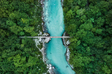Suspension bridge over a blue river in the middle of the forest (Soca valley, Slovenia)