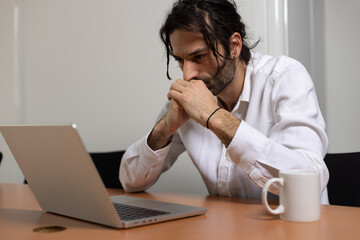 portrait d'un jeune homme, employé de bureau qui travaille assis devant son ordinateur au bureau....