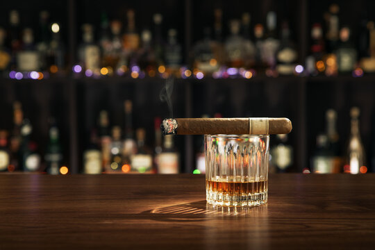 Closed up view of glass of whiskey with cigar on top on white back