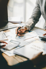 Young colleagues discuss business and analytical price charts using calculators and laptops to calculate financial, tax, accounting, statistics and analytical research ideas.