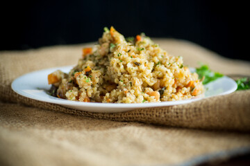 cooked bulgur with vegetables, carrots and dried mushrooms in a plate .