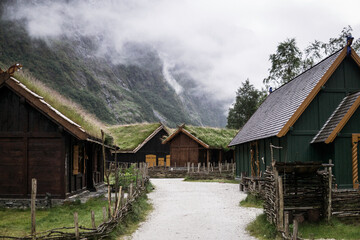 Fototapeta na wymiar Gudvangen, Norway - a viking cottages in the clouds of Nærøyfjord, surrounded by mountains, waterfalls and narrow valleys. Traditional wooden houses showing the medieval life in the viking village.