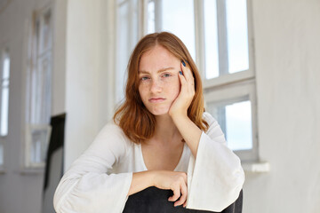 bored young ginger female looking into camera