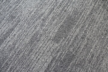 The surface of the carpet is covered with alternating light and dark gray hairs. Shot of short-pile...