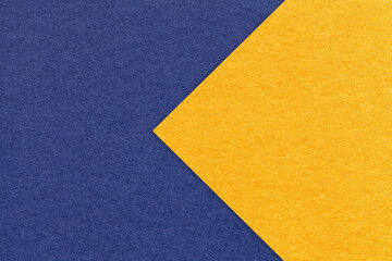 Texture of navy blue paper background, half two colors with yellow arrow, macro. Craft denim and...
