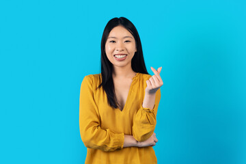 Positive Asian Woman Showing Money Gesture On Blue