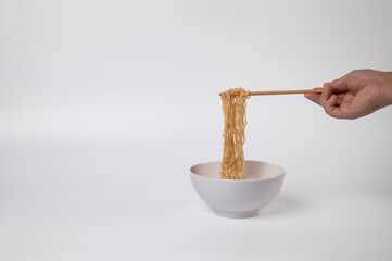 Boiled instant noodles on a white background. Hand takes noodles with chopsticks for food. Fast food. Modern food.