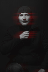 Lifestyle concept. Man with winter hat and black coat studio portrait. Model with beard looking at camera with serious look. Red color split effect style. 3D glitch virtual reality effect