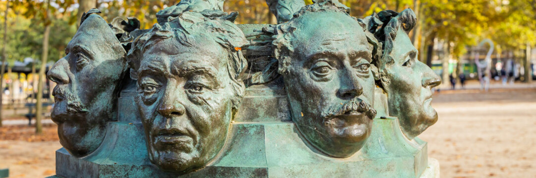 Close up on masks of The Mask Seller statue by Zacharie Astruc in the Luxembourg garden in Paris, France