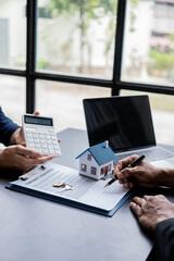 Real estate agents offer contracts and interest rates to buy or rent a residence. and businessman in front of house model, small building concept property and real estate insurance vertical image