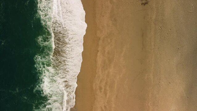 A birds eye view of waves washing a shore in Devon Uk. A quiet beach at summertime