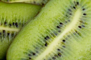 Sliced green ripe kiwi are lying on the table
