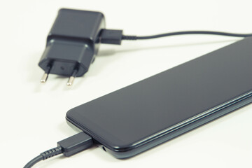 Smartphone with connected plug of charger. Telephone charging