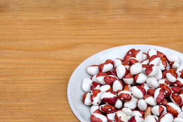 White beans in a bowl. Large Spotted Beans. Protein products. Organic healthy products on a brown background