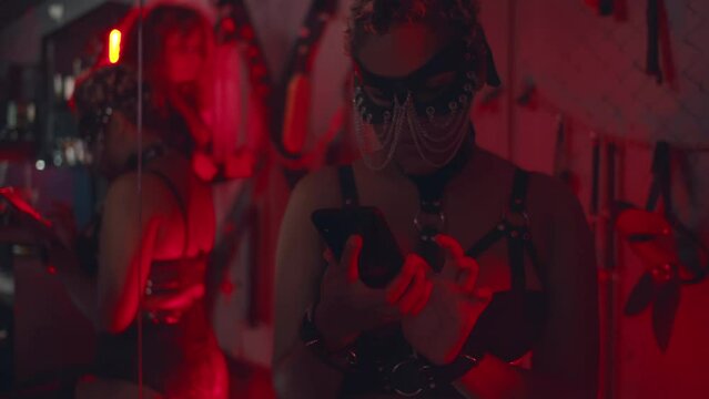 Female stripper of bdsm performant use smartphone in night club. Realtime