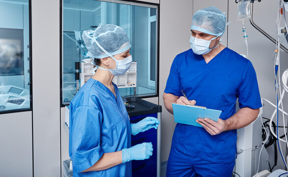 Nurses discussing notes with vital signs of patient in intensive care unit of hospital while working day