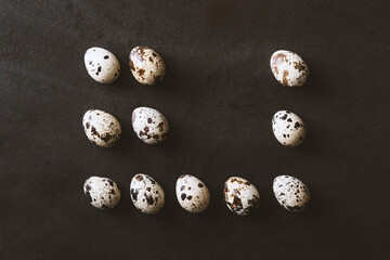 Eggs flat lay on rustic metal black background. Quail and chicken eggs lined up in a row as a rectangle shape