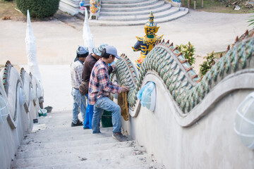 man  gluing ceramic tile on  Naga stair in temple, construction Naga stair in Thailand
