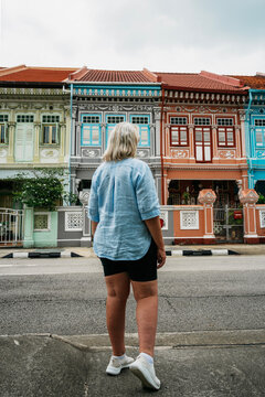 Woman tourist looking at the colourful historical Peranakan streetscape of Koon Seng Road in Singapore.
