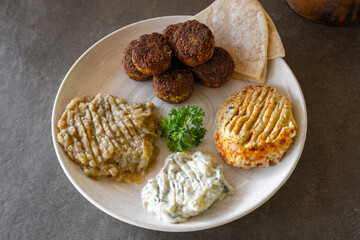 Simple middle eastern plate of food with hummus, falafel, baba ganoush, and tzatziki