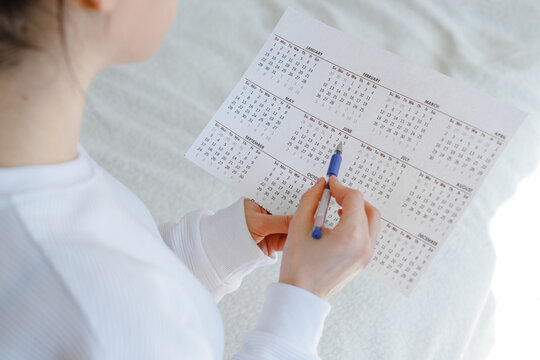 Woman planning her monthly menstruation calendar, mark the days of menstruation and ovulation.